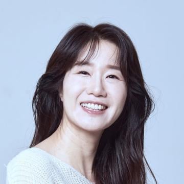 Woman with long black hair and white shirt smiling